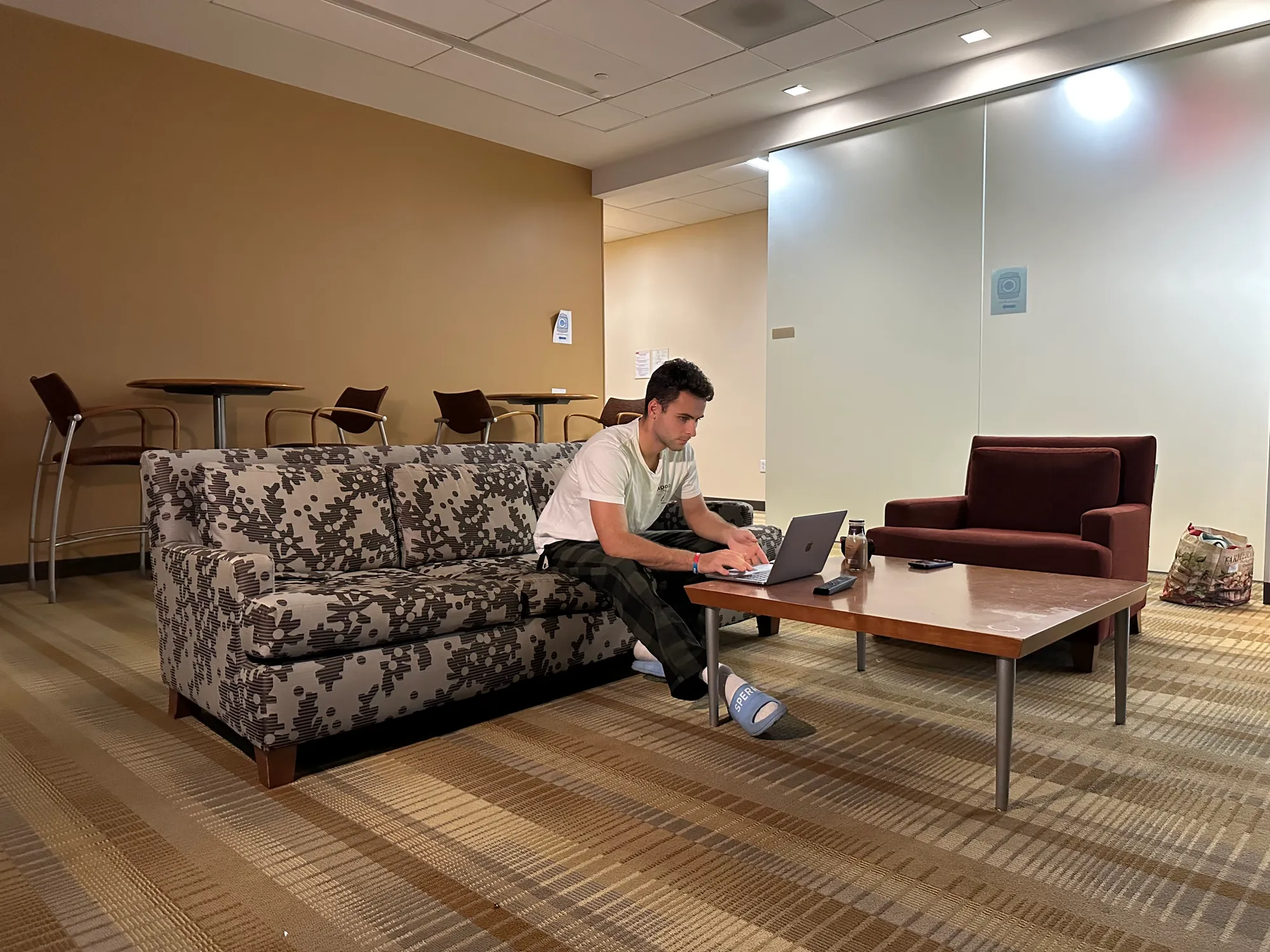 An Elevator Pitch cast member working at a laptop on the lounge set